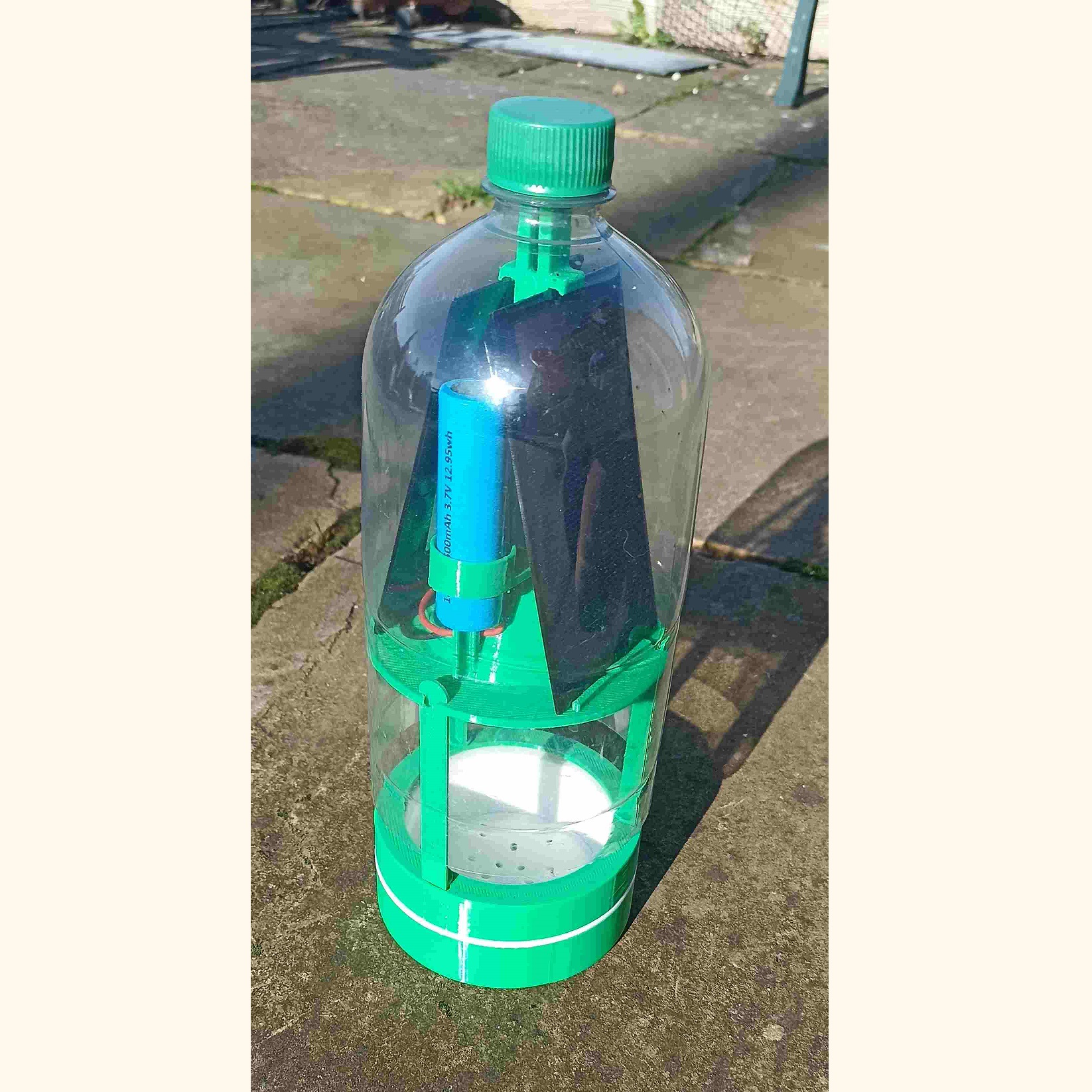 Close-up of the BuzzCopper device showing the 3D-printed frame, ESP32 camera module, and solar battery inside a PET bottle